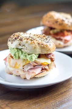 two white plates topped with sandwiches on top of a wooden table