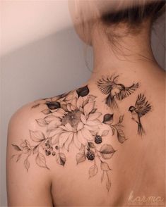 the back of a woman's neck with flowers and birds on it