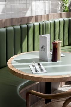 a table with a book, fork and knife on it in front of a green booth