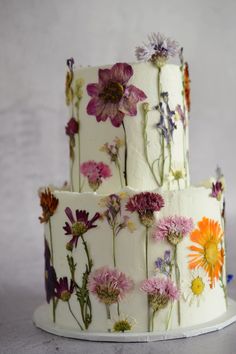 a three tiered cake with flowers painted on it