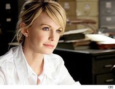 a woman sitting at a desk in an office looking off to the side with blue eyes