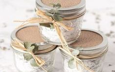 four mason jars are stacked on top of each other with sage leaves tied to them