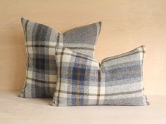 two plaid pillows sitting on top of a bed