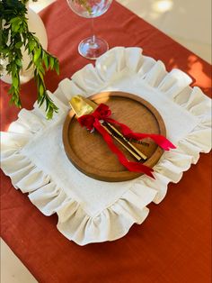 a wooden plate topped with two golden spoons on top of a red table cloth