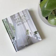 a book sitting on top of a white table next to a potted green plant