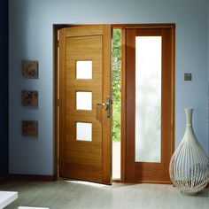 an open wooden door in a blue room with a vase on the floor next to it