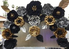 black and gold paper flowers are arranged in a circle on the side of a building