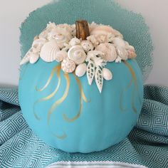 a blue pumpkin decorated with shells and seashells