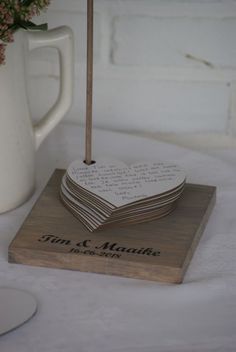 a stack of wooden coasters sitting on top of a table next to a vase with flowers