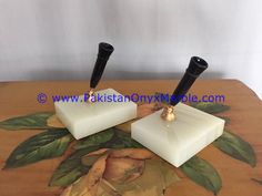 two black and gold candlesticks sitting on top of a wooden table with leaves