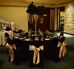 the table is set with black linens and gold bows