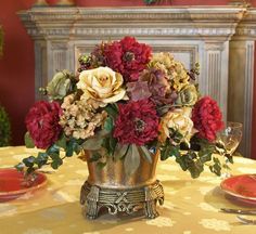 a vase filled with lots of red and yellow flowers on top of a dining room table