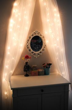 a white dresser topped with a mirror covered in lights