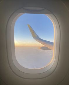 an airplane window looking out at the sky and clouds from inside another plane's wing