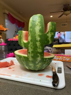 a large watermelon shaped like a cactus sitting on top of a cutting board