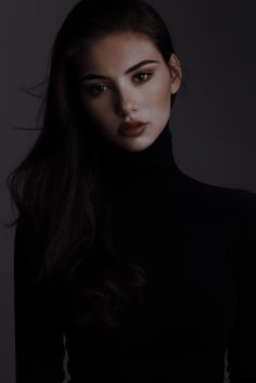 a woman with long dark hair wearing a black turtle neck top and posing for the camera