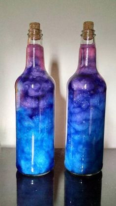 two bottles with blue and purple liquid in them