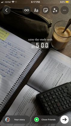 an open notebook and keyboard on a table next to a calculator, cup of coffee and cell phone