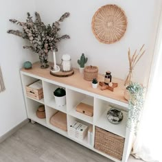 a white shelf with baskets and plants on it