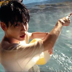 a young boy is holding something in his hand while standing in an indoor swimming pool