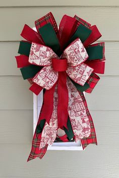 a red and green bow hanging from the side of a house