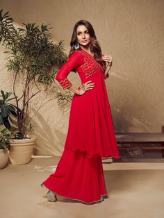 Malaika Arora's red zari embroidered flared kurta with sharara is an elegant winter essential perfect for your ethnic wardrobe. This calf-length A-line piece of pure beauty features a V-neck and three-quarter sleeves that are expertly embroidered with zari and machine weave. Crafted from georgette with crepe inner, it's a timeless addition to your closet. Dry clean only. TOP: Georgette, TOP INNER: Crepe, BOTTOM: Georgette with Crepe Inner, Dry Clean Red Chikankari Embroidery Sharara For Designer Wear, Red Sharara With Straight Kurta For Eid, Red Long Sleeve Sharara For Navratri, Long Sleeve Sharara For Diwali Festive Occasions, Long Sleeve Sharara For Diwali Festive, Long Sleeve Sharara For Festive Diwali, Long Sleeve Sharara For Festive Diwali Celebrations, Festive Red Long Sleeve Palazzo Set, Red Georgette Lehenga With Straight Kurta