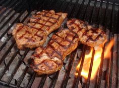 steaks cooking on the grill with flames