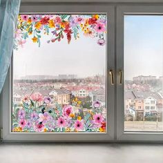 an open window with colorful flowers painted on it and the city in the distance behind