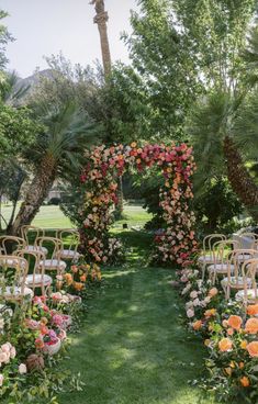 an outdoor ceremony setup with chairs and flowers on the grass, surrounded by palm trees