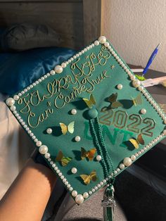 a green graduation cap with gold butterflies on it