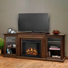 an entertainment center with a fire place and television on the top shelf, in front of a flat screen tv