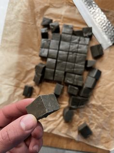 a person holding a piece of chocolate in their hand next to other pieces of chocolate