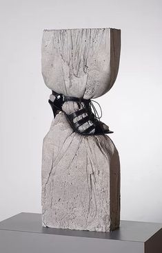 the sculpture is made out of concrete and has black shoes tied to it's sides