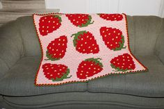 a crocheted strawberry pillow sitting on top of a couch next to a green chair