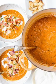 three bowls of soup with bread on the side and one bowl filled with soup in it