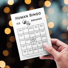 a person holding up a piece of paper that says human bingo ice breaker on it