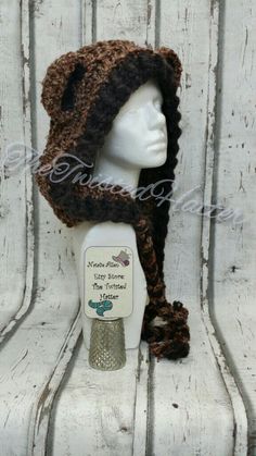 a white mannequin head wearing a brown crocheted hat with ear flaps