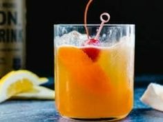 a glass filled with an orange drink and garnished with a cherry on top