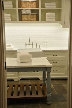 a kitchen with white cabinets and marble counter tops