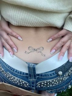 a woman's stomach with a bow tattoo on her lower body and bottom part