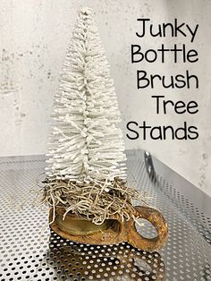 a small white tree sitting on top of a metal table next to a bottle opener