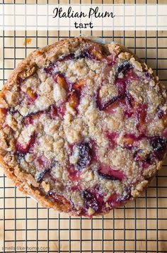 a close up of a pie on a cooling rack with the words italian plum tart above it