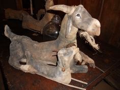 a wooden table topped with an old fashioned statue of a goat and baby sheep sitting next to each other