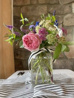 a vase filled with flowers sitting on top of a striped table cloth covered tablecloth