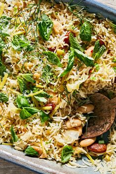 a bowl filled with rice and vegetables on top of a wooden table