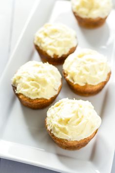 four cupcakes with white frosting on a plate