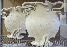 two white vases sitting on top of a metal rack