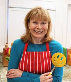 a woman in an apron holding a smiley face lollipop