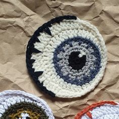 three crocheted bowls with an eye on them sitting on a piece of paper