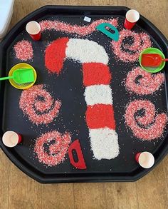 a black tray with red and white sprinkles in the shape of a candy cane